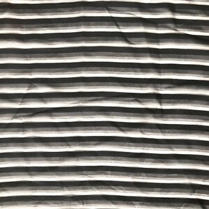 May include: Black and white striped fabric with a subtle gradient effect. The fabric is wrinkled and has a soft, textured appearance.