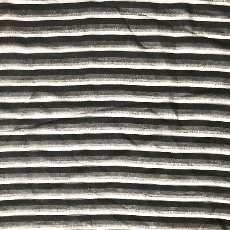 May include: Black and white striped fabric with a subtle gradient effect. The fabric is wrinkled and has a soft, textured appearance.