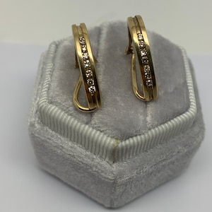 May include: A pair of gold hoop earrings with a row of small diamonds set in the band.