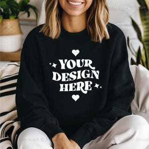 Può includere: Felpa nera con una grafica bianca che dice "YOUR DESIGN HERE" con due piccoli cuori su entrambi i lati del testo.