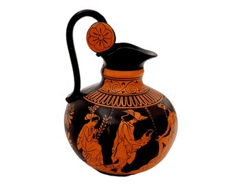 Pode incluir: Jarra de cerâmica grega preta e laranja com uma pega preta e um desenho floral na tampa. A jarra é decorada com uma cena de três figuras em silhueta preta.