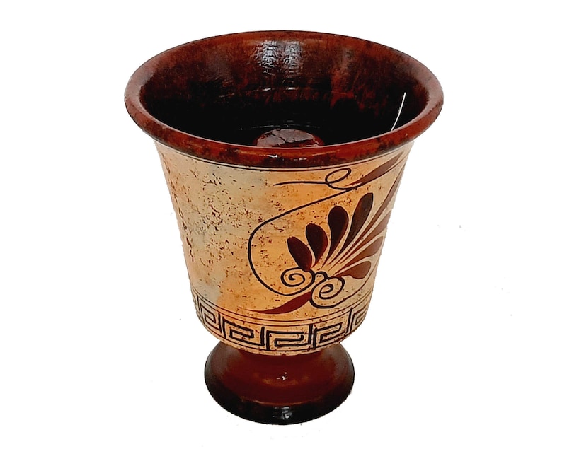 May include: A brown ceramic goblet with a white and brown geometric design. The goblet has a wide base and a narrow top.