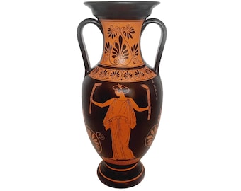 May include: A black and orange Greek amphora with a painted design of a woman holding a staff. The inscription on the vase reads "EKATH".