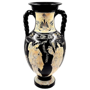 Peut inclure: Vase en amphore grecque noire et dorée avec deux figures en relief. La vase a deux anses en corde et une base noire avec un motif géométrique.