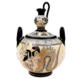 May include: A white ceramic Greek amphora with black and brown painted details. The amphora depicts a scene of a man wrestling a sea serpent. The amphora has two handles and a spout.