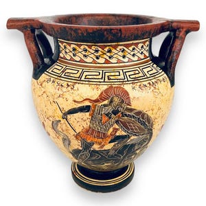 May include: A ceramic vase depicting a warrior scene, with a cream-coloured background and black, red, and orange details. The vase has two handles and a decorative rim. The measurements are in centimetres.