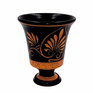Pu&ograve; includere: Un vaso in ceramica nera con un design decorativo arancione. Il vaso ha un'ampia apertura e una base rotonda.