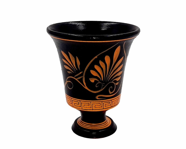 Pu&ograve; includere: Un vaso in ceramica nera con un design decorativo arancione. Il vaso ha un'ampia apertura e una base rotonda.