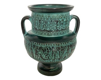 May include: A green ceramic amphora with two handles and intricate black designs. The amphora has a round body and a tall, slender neck.