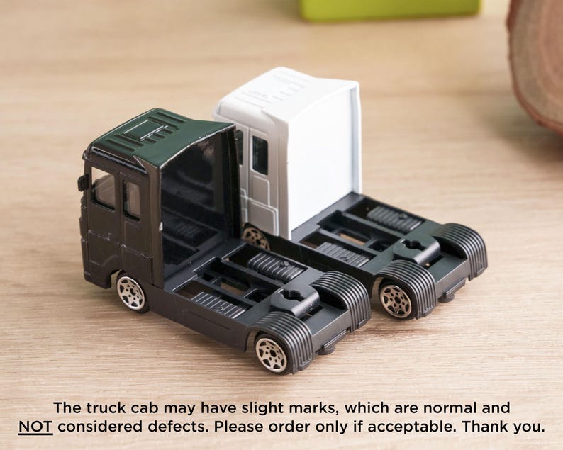 A toy model of a truck cab with two different color options, one black and one white, sitting on a wooden surface.
