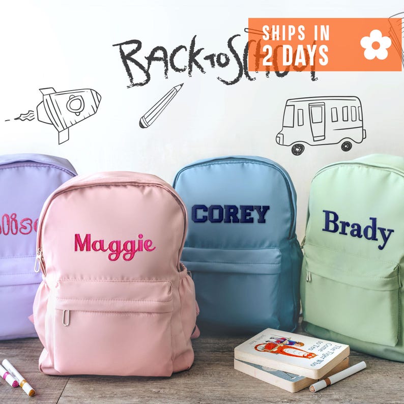 three colorful backpacks with personalized names on them, placed on a wooden surface. Above the backpacks, there is a whiteboard with the text "Back to School" written on it, along with various drawings and illustrations related to school and backpacks.