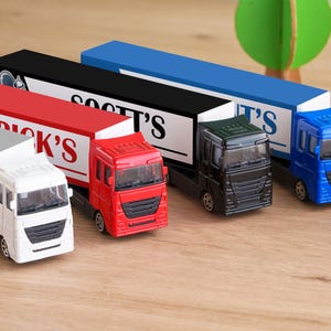 A collection of toy trucks in various colors, including red, white, blue, and black, arranged on a wooden surface.