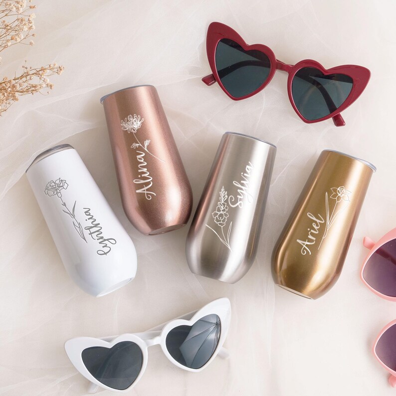 a collection of personalized items, including wine glasses, sunglasses, and a veil, arranged on a light-colored background.
