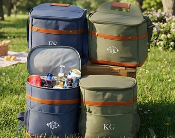 May include: Four insulated cooler bags in navy blue and olive green with brown faux leather trim and top handles. Two bags are closed, one is open revealing assorted beverage cans and bottles, and one is closed. Each bag features white monogram text.