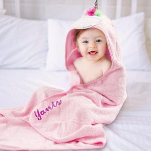 a baby wrapped in a pink towel on a bed