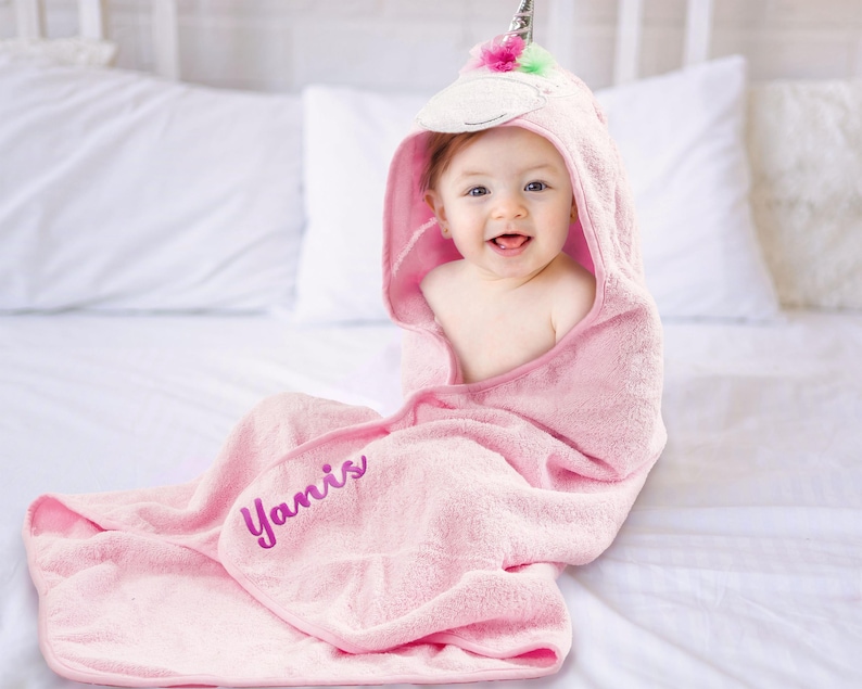 a baby wrapped in a pink towel on a bed