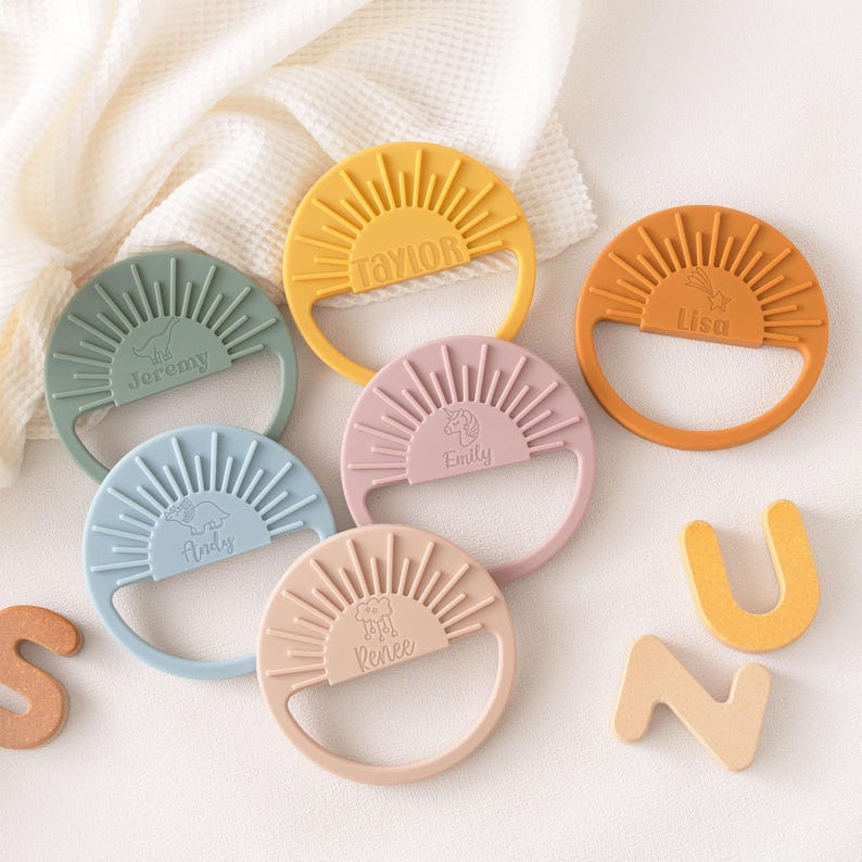 A collection of colorful baby teething rings with names on them, along with some wooden letters on the side.