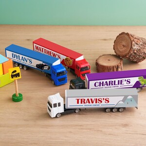 A collection of toy trucks and blocks arranged on a wooden surface, with some labeled with company names.