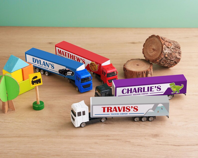 A collection of toy trucks and blocks arranged on a wooden surface, with some labeled with company names.