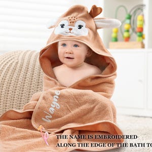 a baby wrapped in a towel with a giraffe face on it