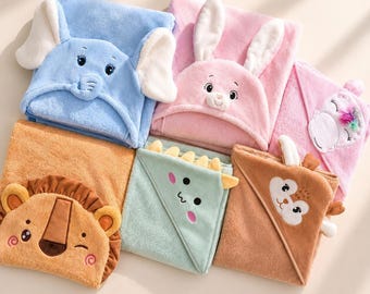 Peut inclure: Une collection de six serviettes à capuche douces présentant des motifs d'animaux, dont un éléphant bleu, un lapin rose, un lion beige, un dinosaure vert, un cerf marron et une licorne rose avec une crinière colorée.