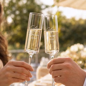 Two people are holding champagne flutes and toasting with a smile, with the text "Celine & Rowan" visible on the glasses.