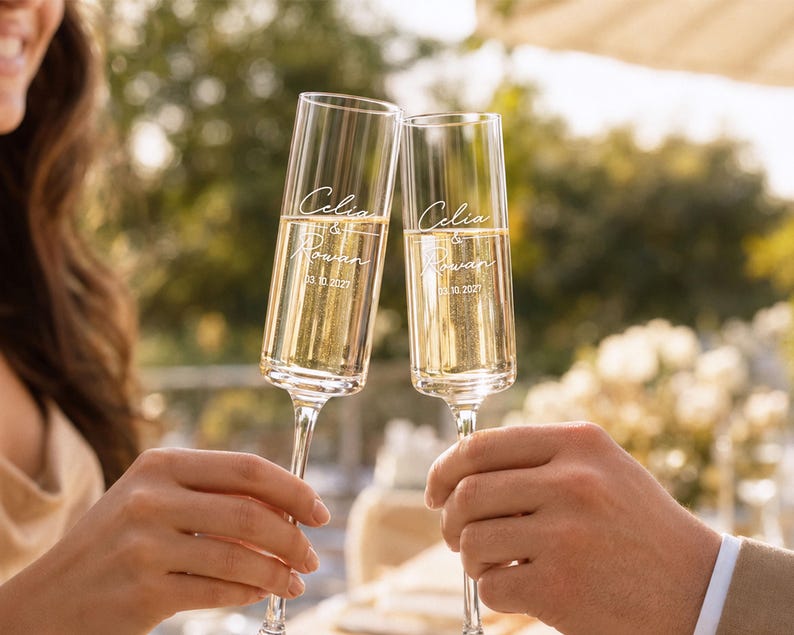 Two people are holding champagne flutes and toasting with a smile, with the text "Celine & Rowan" visible on the glasses.