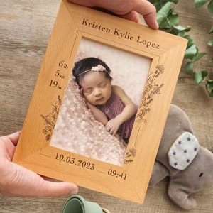 May include: A wooden photo frame with a floral design and engraved text. The frame includes the name "Kristen Kylie Lopez", the date "10.03.2023", the time "09:41", and the baby's measurements: 6 lb, 5 oz, 19 in. A photo of a baby girl is inside the frame.