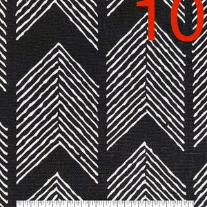 May include: Black fabric with a white chevron pattern. The fabric is measured with a ruler in inches. The number 10 is written in red on the fabric.