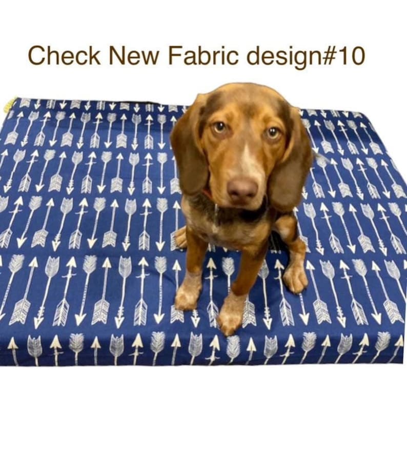 May include: A brown and white dog sitting on a blue dog bed with a white arrow pattern. The bed has a yellow border. The text "Check New Fabric design#10" is visible at the top of the image.