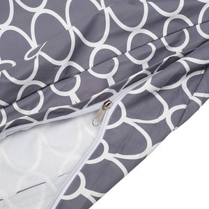 May include: A gray and white patterned fabric with a zipper. The fabric has a repeating pattern of white circles on a gray background.