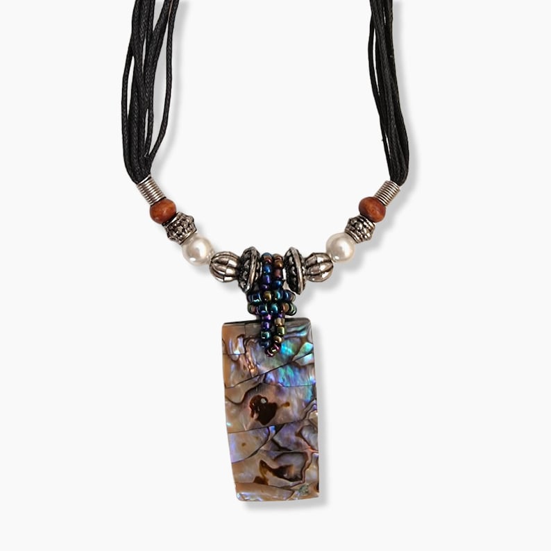 May include: A rectangular pendant necklace with an iridescent abalone shell design. The pendant is suspended from a black cord necklace with wooden beads, silver-toned metal beads, and white pearl beads.