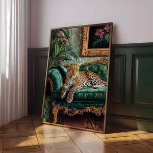 May include: A leopard lounges on a plush green velvet chaise lounge with gold accents. The chaise is in a room with lush green plants and a framed painting.