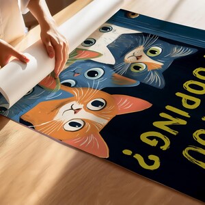 May include: A black and blue poster with three cats peeking out from behind a door. The cats are orange, blue, and white. The text on the poster reads "Are you pooping?" in yellow letters.