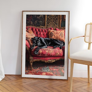 Op de afbeelding: Een ingelijste print met een zwarte panter die rust op een rode, sierlijke bank met kussens met patronen. Het kunstwerk bevindt zich in een kamer met een vloerkleed en wandkunst met patronen, wat een luxe uitstraling creëert. De lijst is lichtbruin.