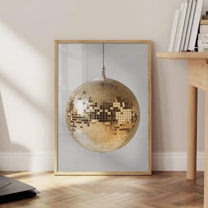 May include: A framed print of a gold disco ball hanging from the ceiling against a white background.