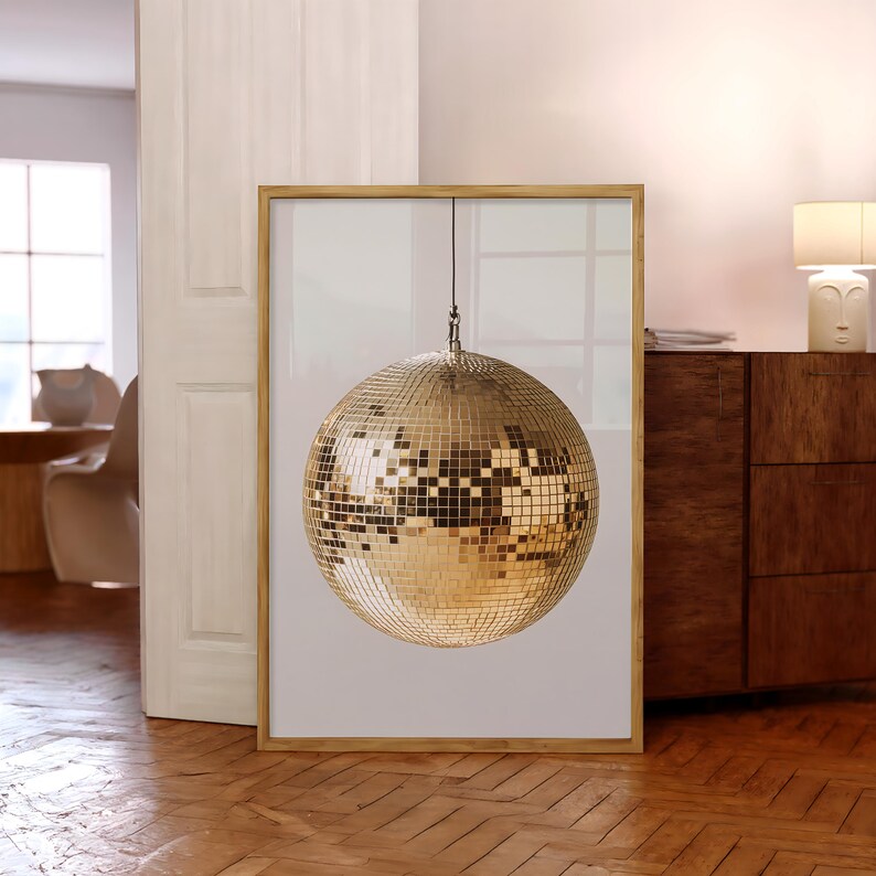 May include: A framed print of a gold disco ball hanging from the ceiling. The disco ball is made of many small mirrors and reflects light in all directions.