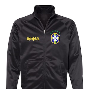 以下が含まれることがあります： 左胸に金色の刺繍で「BRASIL」が施され、右胸に緑、黄、青の刺繍でブラジルのサッカーの紋章が施された黒いジッパー付きジャケット。紋章には白い文字で「CBF」が記されています。