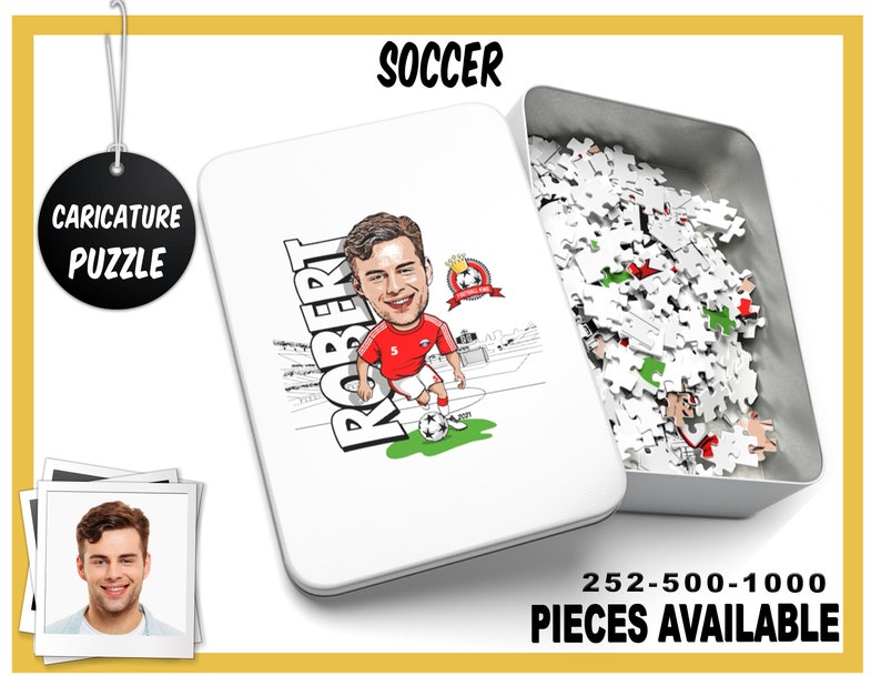 May include: A white metal tin with a caricature of a soccer player on the front. The tin contains a jigsaw puzzle with 252, 500, or 1000 pieces. The text "SOCCER" is at the top of the tin and "CARICATURE PUZZLE" is on a black circle at the top left of the image. The text "ROBERT" is written vertically on the left side of the caricature. The text "252-500-1000 PIECES AVAILABLE" is at the bottom of the tin.