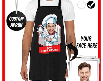 May include: Black apron with a cartoon chef wearing a white chef hat and holding a silver serving tray. The chef's face is replaced with a placeholder image of a man's face. The text "John Chef's Specials" is printed below the cartoon chef.