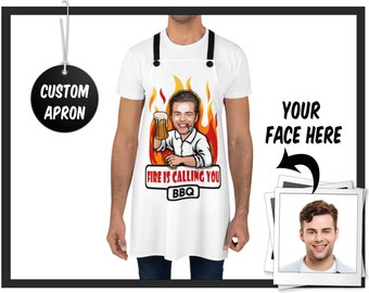 May include: White custom apron with black straps. The apron features a cartoon image of a man holding a beer, with flames in the background and the text "FIRE IS CALLING YOU BBQ". A tag reads "CUSTOM APRON".