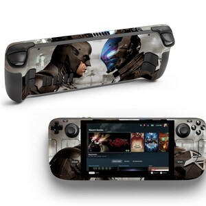 以下が含まれることがあります： 黒と灰色のハンドヘルドゲーム機で、カスタムスキンには、戦闘中の2人の人物の未来的な画像が描かれています。コンソールの画面には、「最近のゲーム」というテキストと、いくつかのゲームタイトルが表示されたメニューが表示されています。