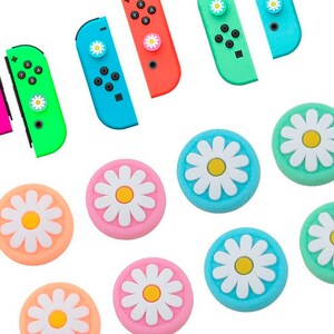 May include: A set of ten colorful daisy-shaped thumb grips for video game controllers. The grips are in pink, blue, green, and light blue colors with white daisy designs.