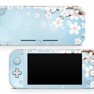 May include: A light blue handheld games console with a floral design. The console has a sky blue background with white cherry blossom flowers and brown branches. The design is on both the front and back of the console.