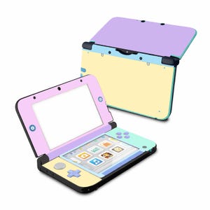Puede incluir: Una consola de juegos portátil de colores pastel con un diseño de concha. La consola presenta una parte superior de color púrpura claro, una parte inferior de color amarillo pálido y una pantalla rodeada por un marco rosa. La pantalla muestra una variedad de iconos de aplicaciones. La consola está abierta, con una segunda en el fondo.