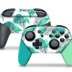 May include: A white Nintendo Switch controller with a tropical leaf design. The controller has green and white accents and features a black joystick and buttons.
