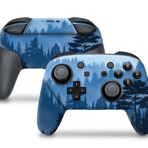 May include: Two wireless game controllers featuring a forest scene design. The controllers have a blue background with a silhouetted forest pattern. The buttons and joysticks are black. The controllers are designed for gaming.