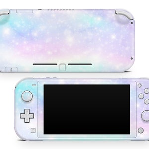 Puede incluir: Una consola Nintendo Switch Lite blanca con un diseño de temática galáctica que presenta un fondo azul pastel, rosa y morado con purpurina blanca. La consola tiene una pantalla negra y botones blancos.