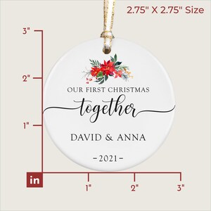Puede incluir: Adorno navide&ntilde;o redondo blanco, de aproximadamente 7 x 7 cm, con un dise&ntilde;o floral de flores de pascua rojas y vegetaci&oacute;n. El texto dice "OUR FIRST CHRISTMAS together DAVID & ANNA -2021-". Se adjunta una cinta dorada.