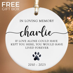 May include: White ceramic ornament with black text that reads "In loving memory charlie If love alone could have kept you here, you would have lived forever 2010-2023". A black paw print is in the center of the ornament.